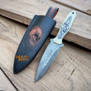 A Tactical Dagger Knife with a stainless Damascus steel blade, skull-engraved camel bone handle, and a custom leather sheath featuring a skull engraving.